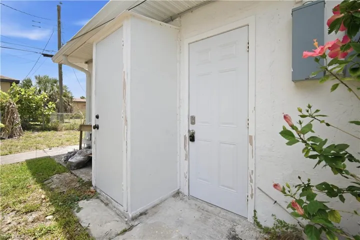 White paneled exterior door with a dark handle, framed by a concrete patio