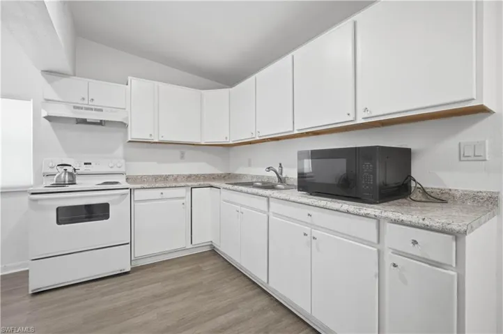 Kitchen featuring white cabinetry, a white range with an overhead vent, and wood-finish flooring