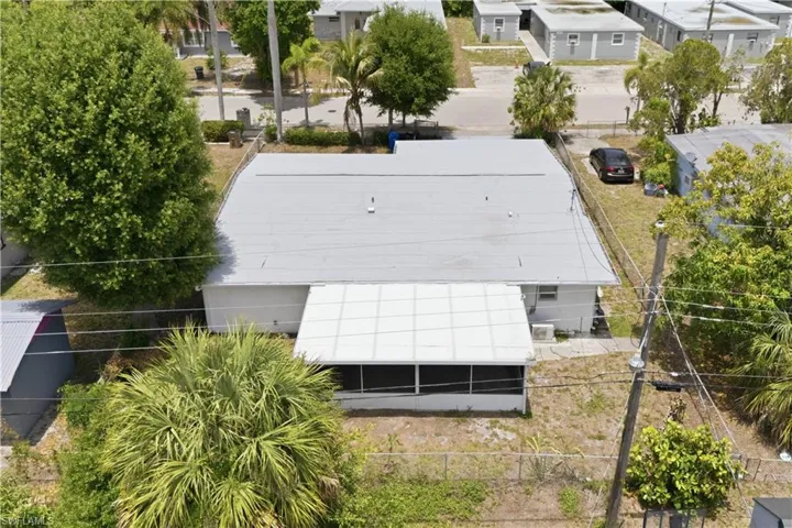 Property featuring a light-colored roof, exterior fencing, and a screened-in porch with a white aluminum frame