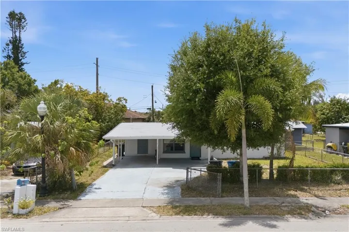 Single-story residence featuring a carport, concrete driveway, and mature landscaping