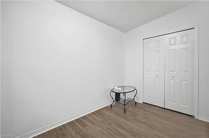 Spacious room featuring wood-finish flooring, white walls, and a ceiling