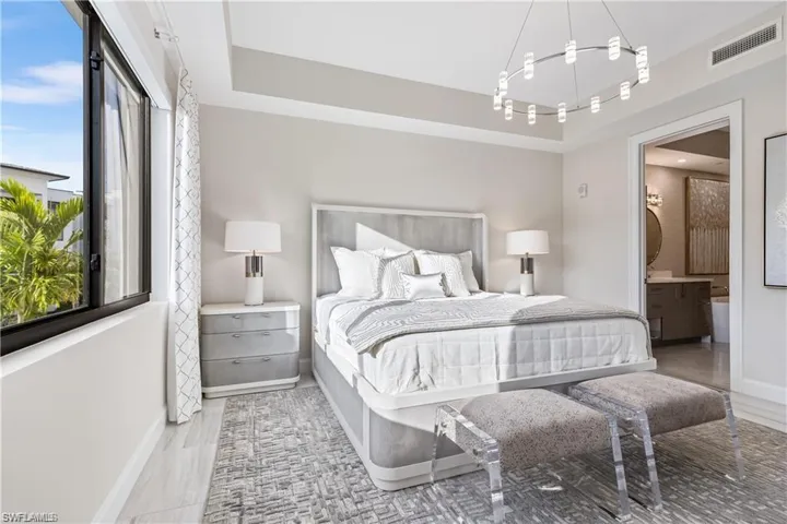 Bedroom featuring a raised ceiling, connected bathroom, and light wood-type flooring