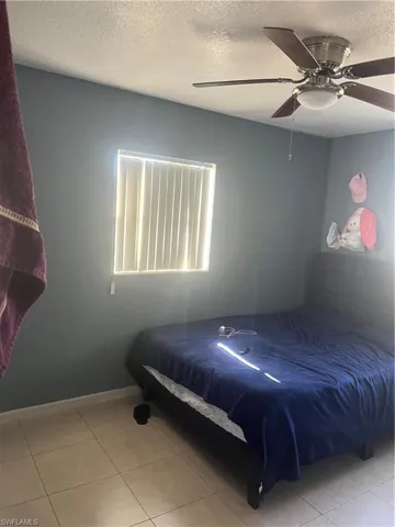 Bedroom featuring a textured ceiling, ceiling fan, and light tile patterned floors