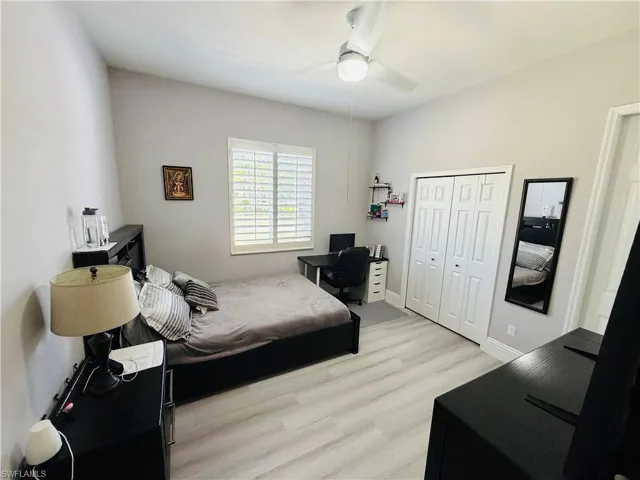 Bedroom featuring light wood finished floors, an office area, a closet, and a ceiling fan