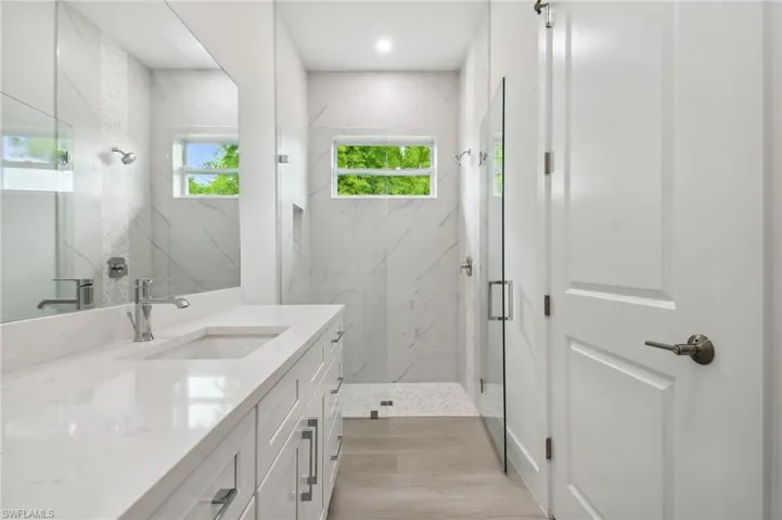 Bathroom with vanity, hardwood / wood-style flooring, and an enclosed shower