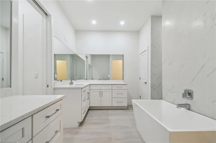 Bathroom with vanity, hardwood / wood-style flooring, and a bathing tub