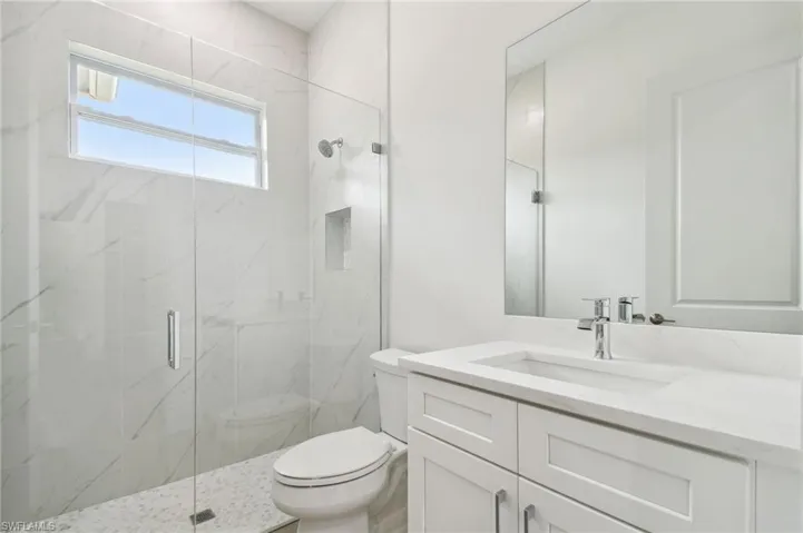 Bathroom with toilet, walk in shower, and vanity