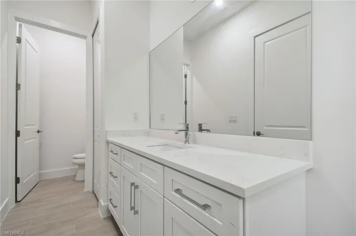 Bathroom with toilet, vanity, and wood-type flooring