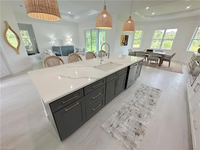 Kitchen with a tray ceiling, a kitchen island with sink, sink, and dishwasher