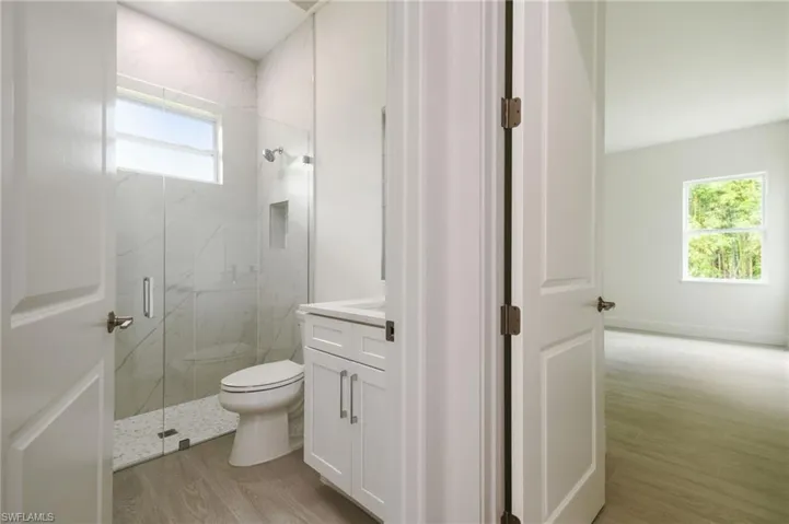 Bathroom featuring vanity, an enclosed shower, hardwood / wood-style floors, and toilet