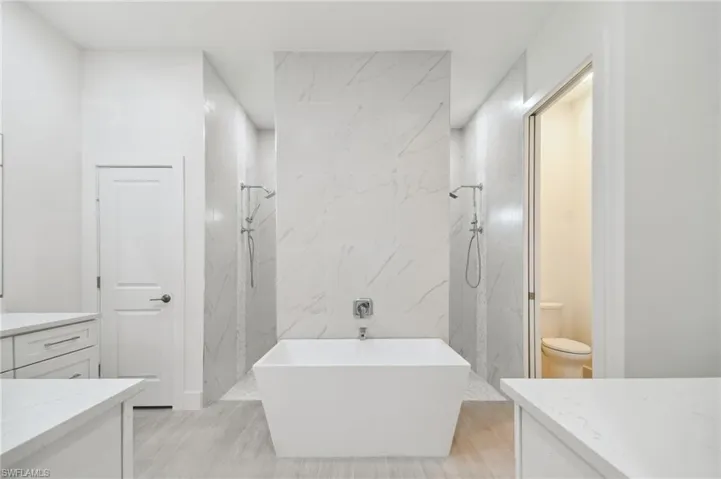 Full bathroom with vanity, toilet, wood-type flooring, and shower with separate bathtub