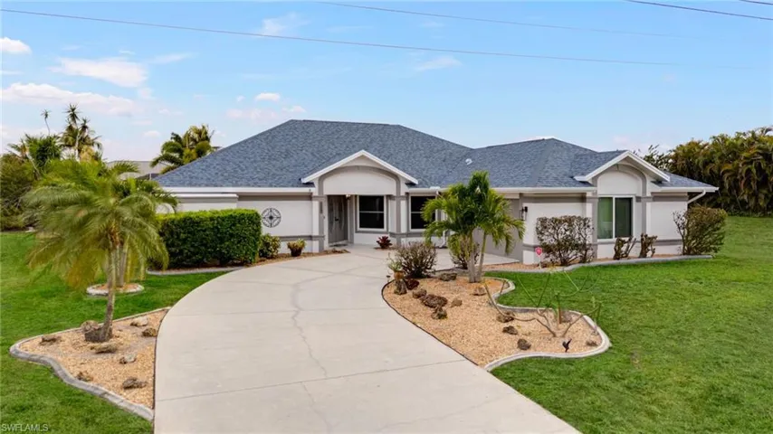 Single story home featuring a front lawn, stucco siding, roof with shingles, and concrete driveway