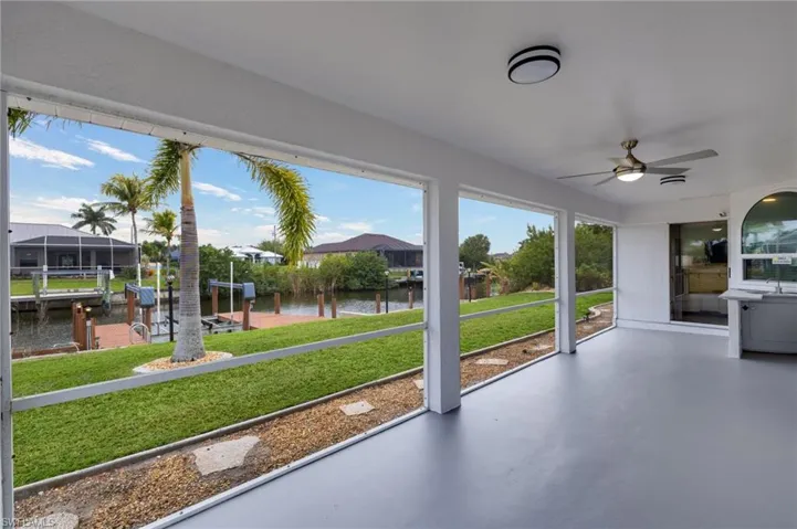 Unfurnished sunroom featuring ceiling fan, a water view, and a patio