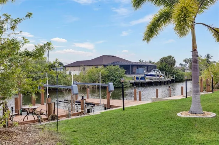 Dock area featuring a lawn, boat lift, and a water view