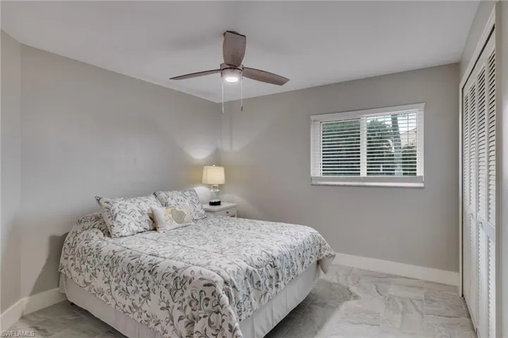 Bedroom featuring a closet, light marble finish floors, and a ceiling fan
