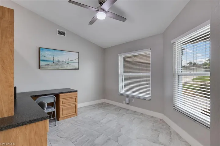 Unfurnished office with lofted ceiling, a ceiling fan, and light marble finish floors