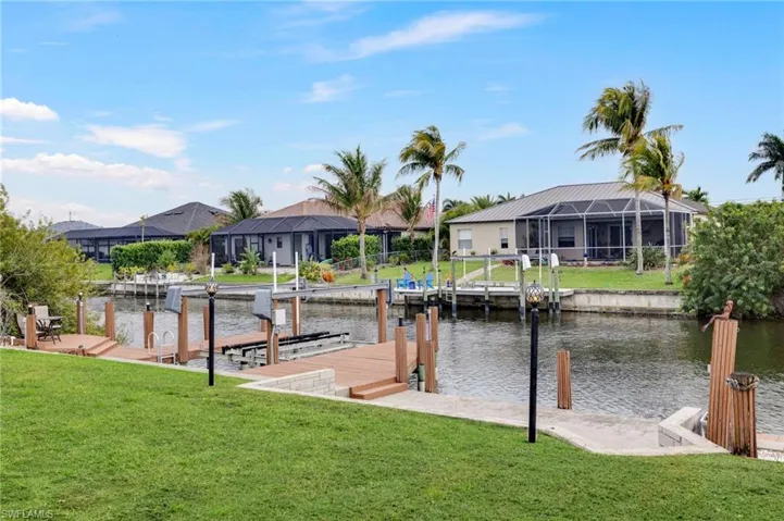 Dock featuring a yard, a water view, a residential view, and boat lift