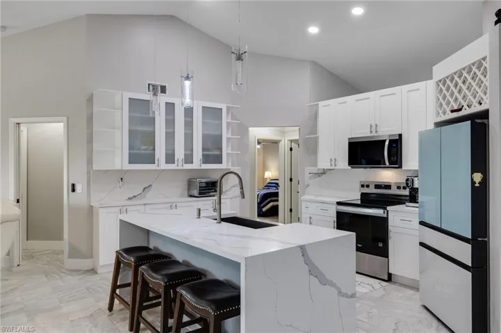 Kitchen with open shelves, white cabinets, stainless steel appliances, and vaulted ceiling