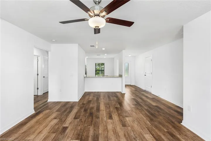 Unfurnished living room with ceiling fan and dark hardwood / wood-style floors