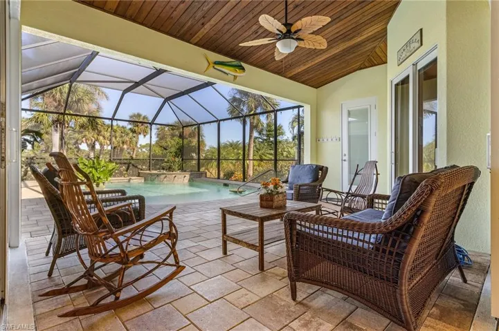 View of patio with screened cage enclosure and ceiling fan