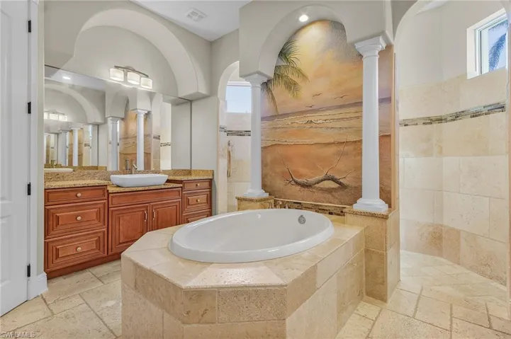 Bathroom with vanity, shower with separate bathtub, and decorative columns