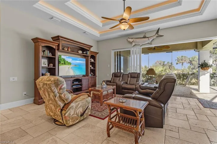 Family room featuring tray ceiling with 90 degree sliders opening to pool and covered lanai
