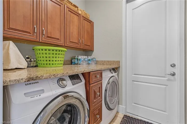 Utility room with custom cabinets, washer and dryer and granite countertop