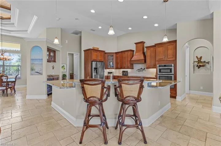 Kitchen with custom cabinetry and range hood and stainless-steel appliances