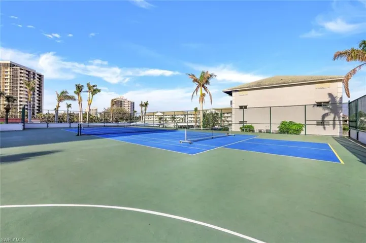 View of tennis court featuring basketball hoop