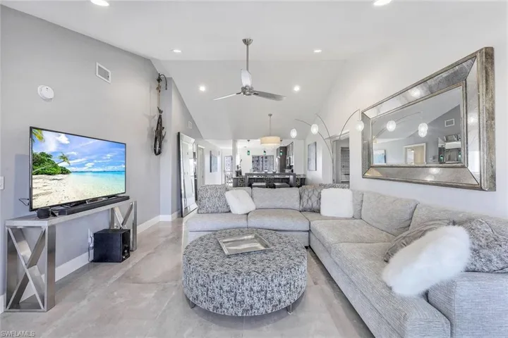 Living room featuring ceiling fan and high vaulted ceiling