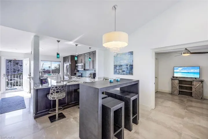 Kitchen with a kitchen breakfast bar, hanging light fixtures, dark brown cabinetry, and stainless steel appliances