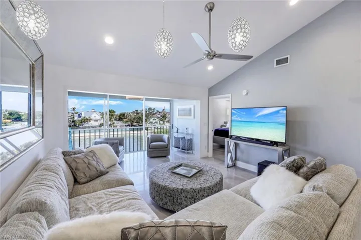 Living room featuring ceiling fan and high vaulted ceiling
