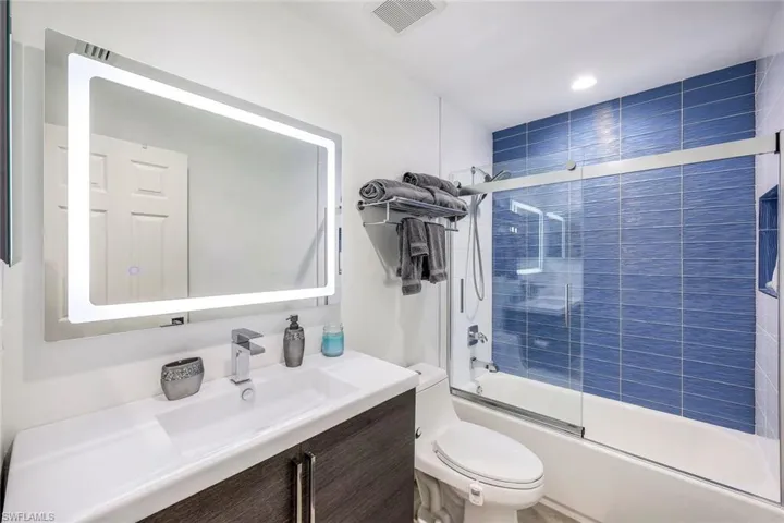 Full bathroom featuring toilet, bath / shower combo with glass door, and vanity