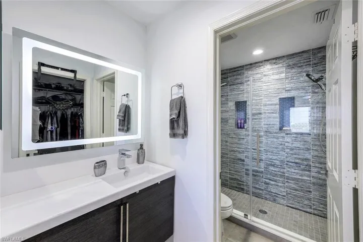 Bathroom with toilet, tile patterned floors, walk in shower, and vanity