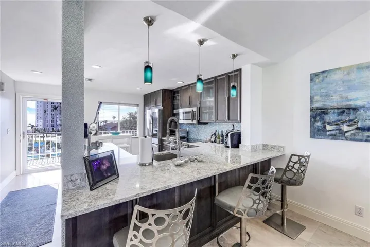 Kitchen featuring a breakfast bar, kitchen peninsula, decorative backsplash, dark brown cabinetry, and appliances with stainless steel finishes