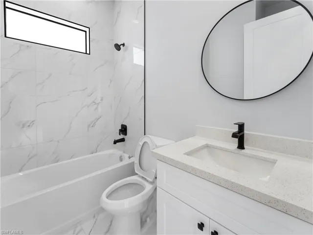 Full bathroom featuring vanity, tiled shower / bath combo, and toilet