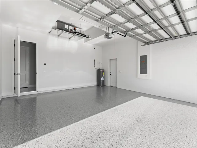 Garage featuring a garage door opener, electric panel, and water heater