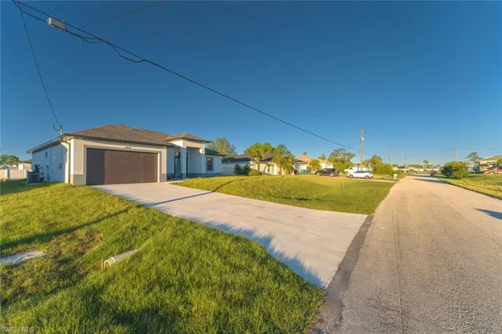 View of front of property featuring a garage, a front lawn, and central air condition unit