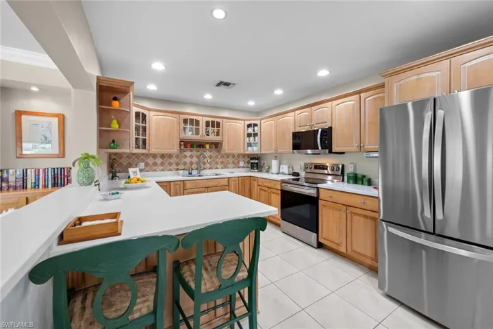 Kitchen with sink, a breakfast bar area, light tile patterned floors, kitchen peninsula, and stainless steel appliances