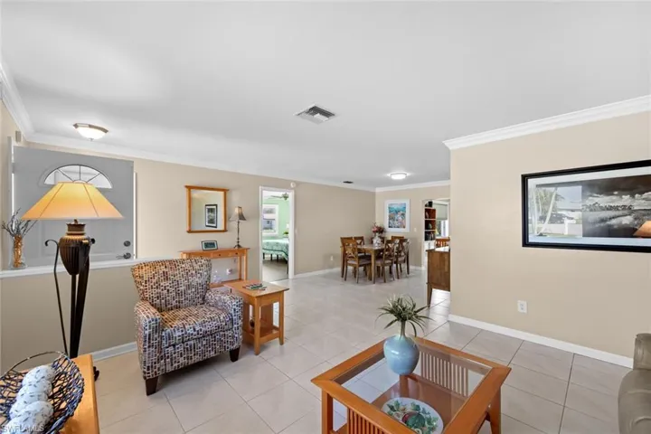 Living room with light tile patterned floors and crown molding