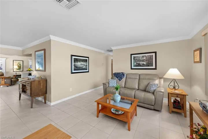 Living room with crown molding and light tile patterned floors