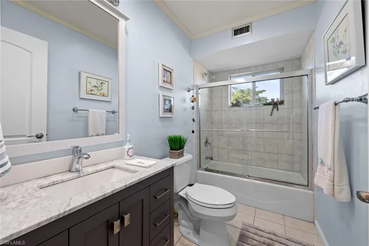 Full bathroom featuring vanity, tile patterned floors, crown molding, toilet, and enclosed tub / shower combo