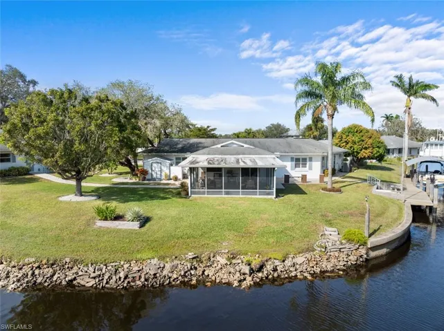 Back of property with a yard, a water view, and a sunroom
