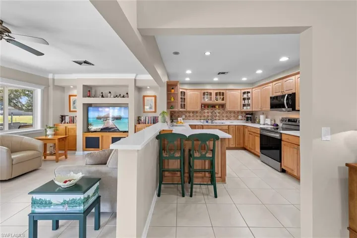 Kitchen featuring electric range, ceiling fan, sink, a breakfast bar, and light tile patterned flooring