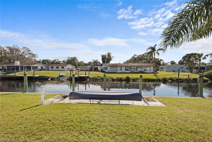 View of dock with a lawn and a water view