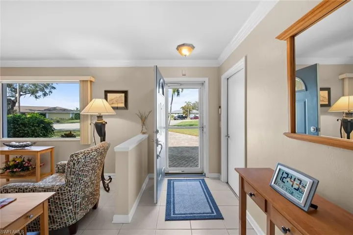 Foyer entrance with light tile patterned floors and ornamental molding