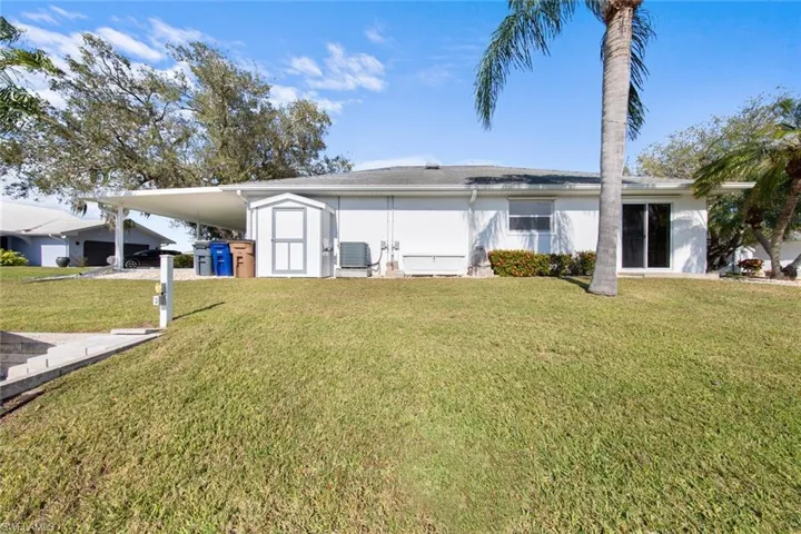 Back of house with a lawn, central AC unit, and a storage shed