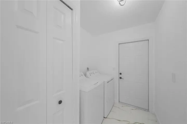 Laundry room featuring light marble finish floors and washer and dryer