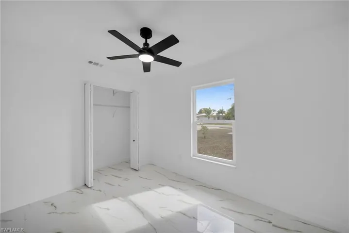 Unfurnished bedroom with marble finish floors, a closet, and ceiling fan