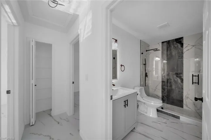 Full bath featuring a marble finish shower, vanity, and light marble finish flooring